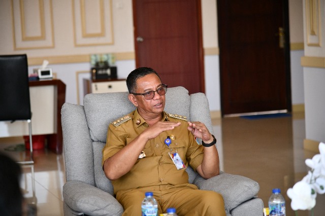 Foto 1: Bupati Bolaang Mongondow Timur (Boltim) Oskar Manoppo, S.E., M.M., tengah berbicara dengan serius saat menerima kunjungan kerja di Ruang Kerja Bupati Boltim. Dalam pertemuan tersebut, Bupati Manoppo menyampaikan beberapa hal terkait tata kelola pemerintahan kepada tamu yang hadir.