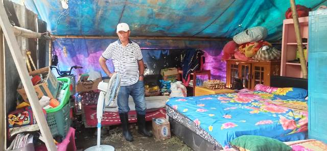 Bupati Oskar Manopo berdiri di dalam tenda pengungsian yang digunakan oleh salah satu keluarga terdampak banjir. Foto ini menunjukkan kehidupan sementara yang dijalani oleh warga yang kehilangan rumah akibat bencana.