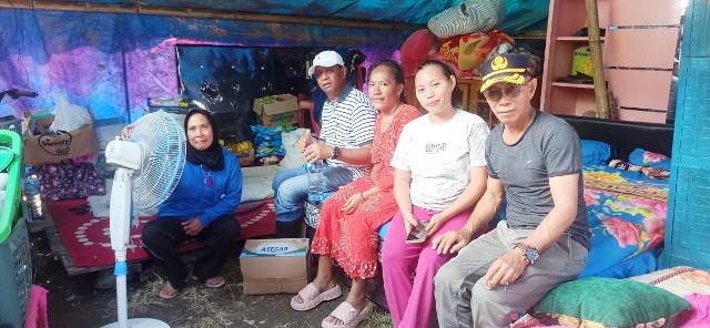 upati Oskar Manopo (kaos putih bergaris hitam, topi putih) duduk bersama keluarga terdampak banjir di dalam tenda pengungsian. Kehadiran Bupati Boltim memberikan semangat dan dukungan bagi warga yang tengah mengalami kesulitan pasca-bencana.