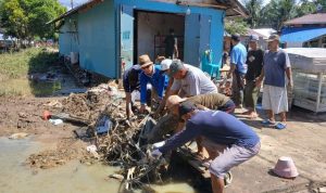 Aparat Desa Tutuyan mengangkut sampah dan lumpur dari area terdampak banjir. Gotong royong dilakukan bersama warga.