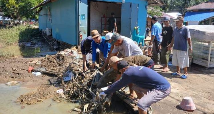 Aparat Desa Tutuyan mengangkut sampah dan lumpur dari area terdampak banjir. Gotong royong dilakukan bersama warga.