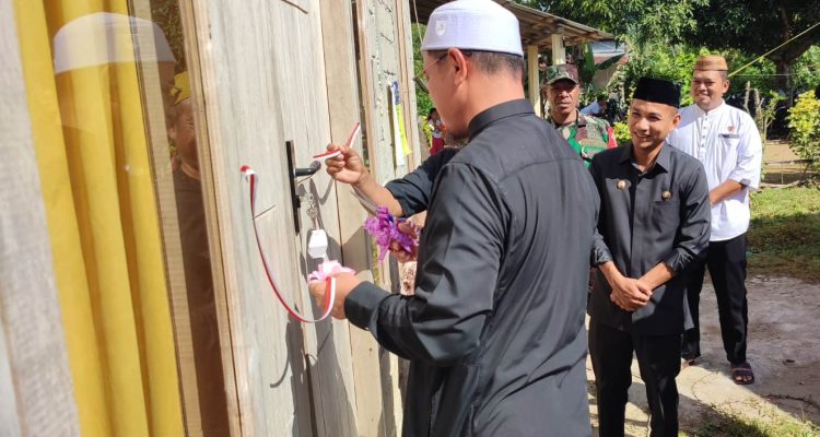 Bupati Bolmut Sirajudin Lasena didampingi Wakil Bupati Moh. Aditya Pontoh melakukan penyerahan simbolis kunci rumah layak huni kepada warga Desa Tuntung dengan memotong pita di depan rumah baru yang telah selesai dibangun. Prosesi ini merupakan bagian dari program rehabilitasi Rumah Tidak Layak Huni (RTLH) yang bertujuan meningkatkan kualitas hidup masyarakat.