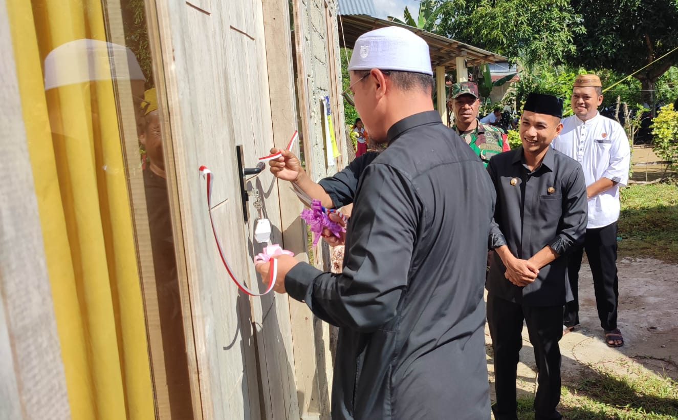 Bupati Bolmut Sirajudin Lasena didampingi Wakil Bupati Moh. Aditya Pontoh melakukan penyerahan simbolis kunci rumah layak huni kepada warga Desa Tuntung dengan memotong pita di depan rumah baru yang telah selesai dibangun. Prosesi ini merupakan bagian dari program rehabilitasi Rumah Tidak Layak Huni (RTLH) yang bertujuan meningkatkan kualitas hidup masyarakat.