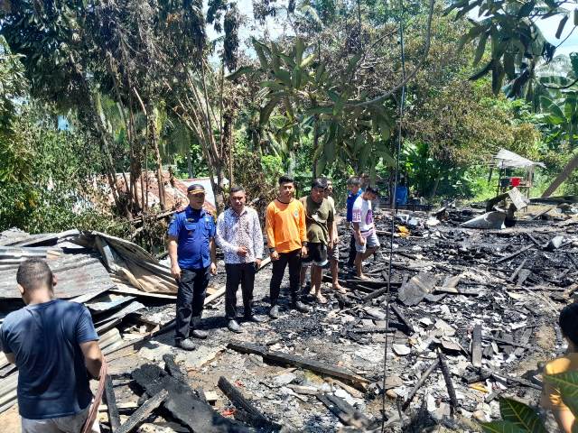 Warga dan aparat desa meninjau lokasi rumah milik keluarga Dolfi Sumaga - Tempomisa yang ludes terbakar di Dusun IV, Desa Dodap Mikasa, Kecamatan Tutuyan, Kamis, (1/5/2025). Kebakaran ini menyebabkan kerugian mencapai sekitar Rp100 juta.