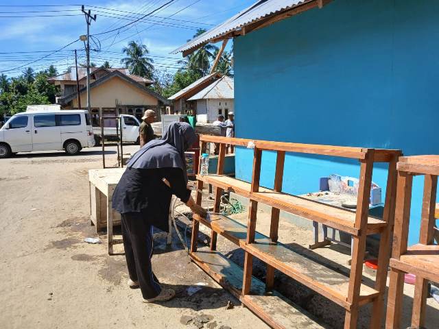 Pemerintah Desa Tutuyan dan warga membersihkan lingkungan sekitar rumah yang masih dipenuhi sisa banjir.