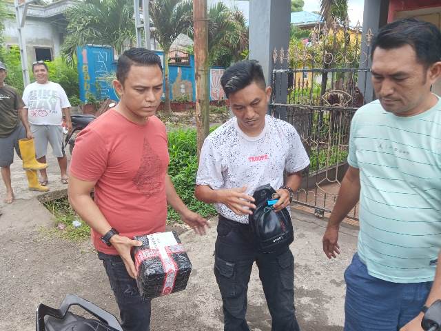 Kasat Resnarkoba IPTU Trivo Datukramat (kiri) bersama tim mengamankan pelaku dan barang bukti usai pengambilan paket kiriman di wilayah Girian Permai.