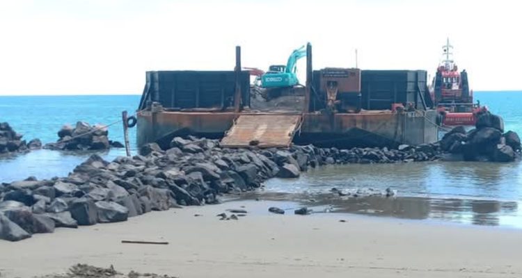 Pemerintah Kabupaten Bolaang Mongondow Utara menagih pajak mineral bukan logam dan batu dari kontraktor proyek APBN di Batu Pinagut. Namun, kontraktor mempertanyakan dasar hukum kebijakan itu karena material diperoleh dari penambang lokal yang belum berizin. Kebijakan ini dinilai tidak konsisten.