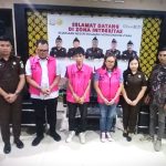 Tiga tersangka kasus dugaan korupsi proyek PAMSIMAS 2022 di Kabupaten Bolaang Mongondow Utara mengenakan rompi tahanan merah muda dengan nomor urut 02, 01, dan 05 saat berfoto bersama aparat Kejaksaan Negeri Bolmut, petugas kepolisian, dan staf kejaksaan, usai penahanan resmi di Kantor Kejari Bolmut, Selasa (01/7/2025).