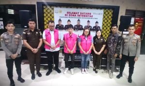 Tiga tersangka kasus dugaan korupsi proyek PAMSIMAS 2022 di Kabupaten Bolaang Mongondow Utara mengenakan rompi tahanan merah muda dengan nomor urut 02, 01, dan 05 saat berfoto bersama aparat Kejaksaan Negeri Bolmut, petugas kepolisian, dan staf kejaksaan, usai penahanan resmi di Kantor Kejari Bolmut, Selasa (01/7/2025).