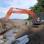 Pekerja proyek bersama alat berat ekskavator menata batu bolder pada pembangunan pengaman pantai di kawasan Batu Pinagut, Desa Boroko Timur, Kecamatan Kaidipang, Kabupaten Bolaang Mongondow Utara. Proyek ini telah mencapai progres fisik 50,05 persen dan berjalan tanpa kendala. (Foto: dok. binadow.com)