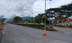 Kondisi ruas jalan di kompleks perkantoran Pemerintah Kabupaten Bolaang Mongondow Utara, Rabu, (6/8/2025), setelah batang dan ranting pohon hasil penebangan dibersihkan. Sebelumnya, tumpukan kayu sempat menghalangi akses jalan di depan sejumlah kantor OPD. Tampak asap sisa pembakaran limbah kayu masih mengepul di kejauhan.
