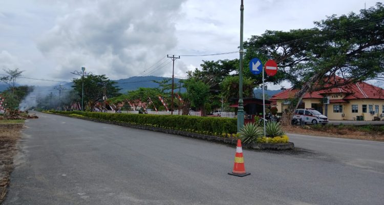 Kondisi ruas jalan di kompleks perkantoran Pemerintah Kabupaten Bolaang Mongondow Utara, Rabu, (6/8/2025), setelah batang dan ranting pohon hasil penebangan dibersihkan. Sebelumnya, tumpukan kayu sempat menghalangi akses jalan di depan sejumlah kantor OPD. Tampak asap sisa pembakaran limbah kayu masih mengepul di kejauhan.