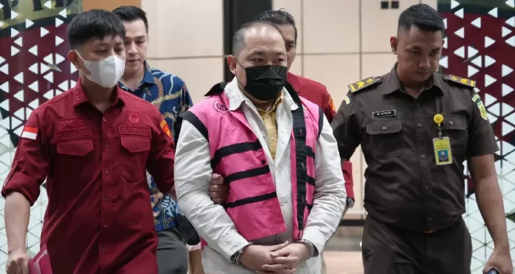 Tersangka kasus TPPU Sritex mengenakan rompi tahanan pink dikawal petugas Kejaksaan saat berjalan di dalam gedung.