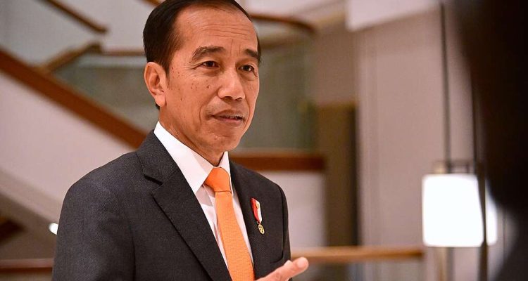 oko Widodo mengenakan jas abu-abu dan dasi oranye sedang berbicara di dalam ruangan