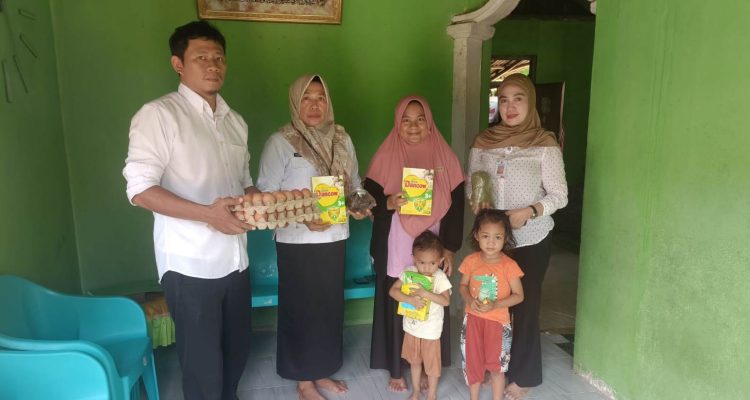 Plt. Kepala Dinas Ketahanan Pangan Bolaang Mongondow Utara, Yulin Kohongia, SE, didampingi petugas saat menyerahkan bantuan pangan bergizi kepada keluarga penerima balita stunting di salah satu desa, Rabu (10/9/2025).