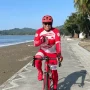 Amin Lasena di atas sepeda di tepi Pantai Batu Pinagut, satu kaki berjinjit, satu tangan
