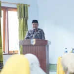 Asisten Administrasi Umum Boltara Abdul Nazarudin Maloho berdiri di podium menyampaikan sambutan pada pembukaan Program Pelatihan Mahasiswa Berdampak UDK 2025 di Desa Bigo Selatan.