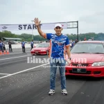 Ketua Panitia Kejurda Drag Race dan Drag Bike Piala Bupati Boltara 2025, Subhan Hasan, melambaikan tangan di garis start lintasan Jl. WR Supratman, Boroko Timur, sebelum dimulainya sesi latihan resmi.
