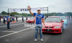 Ketua Panitia Kejurda Drag Race dan Drag Bike Piala Bupati Boltara 2025, Subhan Hasan, melambaikan tangan di garis start lintasan Jl. WR Supratman, Boroko Timur, sebelum dimulainya sesi latihan resmi.