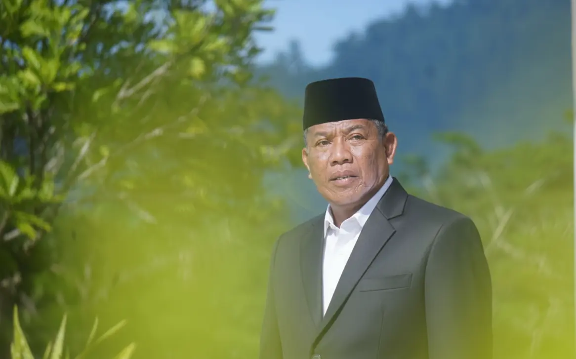 Wakil Ketua DPRD Boltara, Drs. Hi. Depri Pontoh, mengenakan setelan jas hitam dan peci hitam berpose di luar ruangan dengan latar pepohonan hijau.