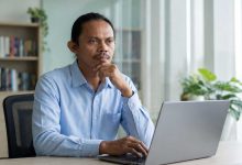 Satrin Lasama Ketua DK PWI Sulut sedang berpikir serius di depan laptop terkait desakan penegakan hukum kasus penghalangan wartawan