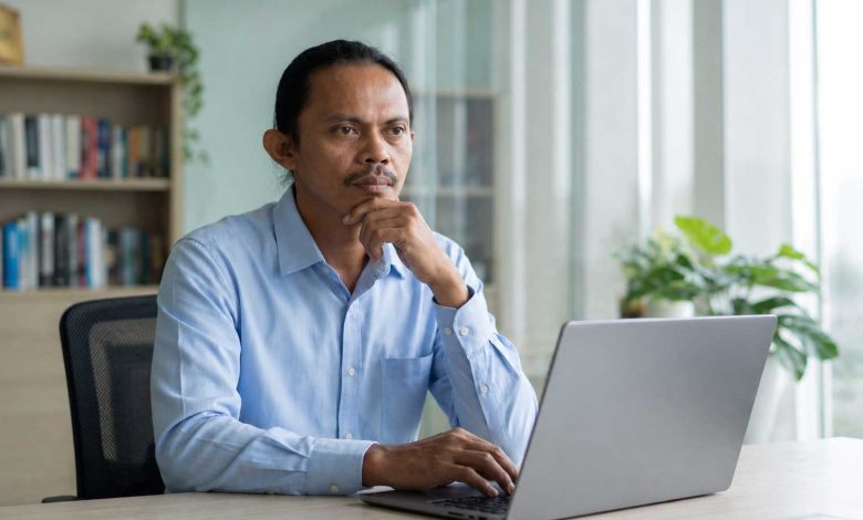 Satrin Lasama Ketua DK PWI Sulut sedang berpikir serius di depan laptop terkait desakan penegakan hukum kasus penghalangan wartawan