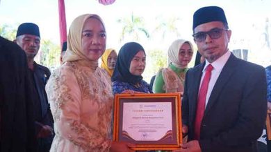 Bupati Bolmut Sirajudin Lasena menyerahkan piagam penghargaan kepada Kadis P3A Yani Lasama pada upacara Hari Kartini dan apel Korpri di halaman Kantor Bupati Bolmut.