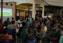 Warga bersama personel Polsek Pinogaluman mengikuti nonton bareng pertandingan FIFA World Cup 2026 di halaman Mako Polsek Pinogaluman, Selasa dini hari, (23/6/2026).